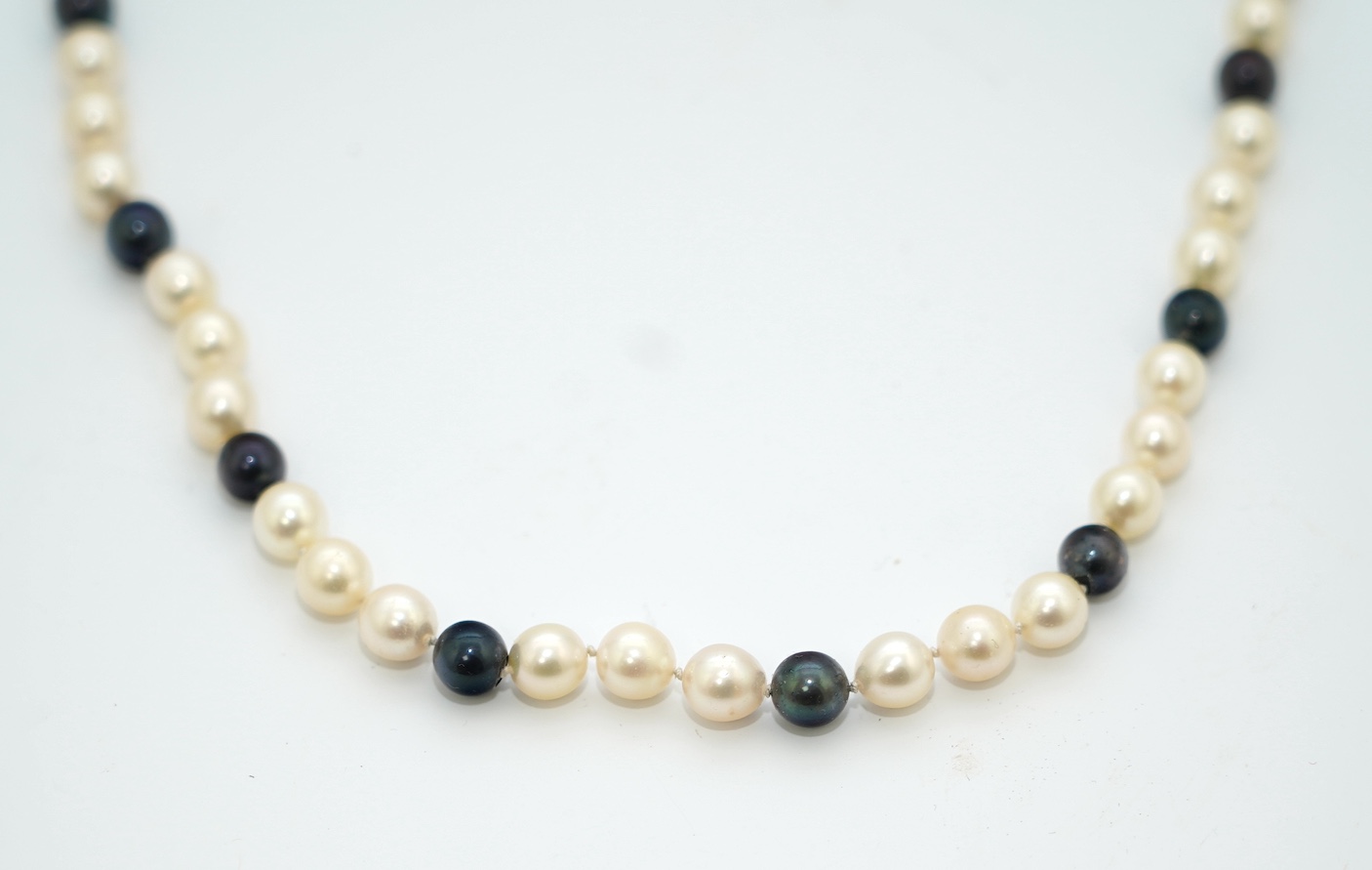 A modern single strand two colour cultured pearl necklace, with 750 yellow metal clasp, 58cm. Condition - fair